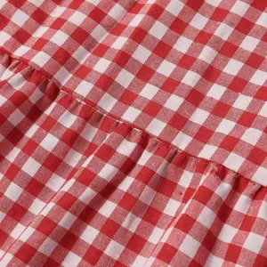 Red and white gingham plaid fabric detail, close up view of pleated dress material