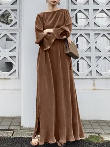 Detailed view of the elegant brown pleated kaftan dress worn by model in outdoor scene.