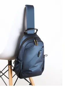 Close-up view of a stylish blue sling backpack hanging on a chair, showing durable design.