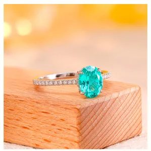 Close up of a stunning oval lab grown paraiba gemstone ring with sparkling pave set diamonds on sterling silver.