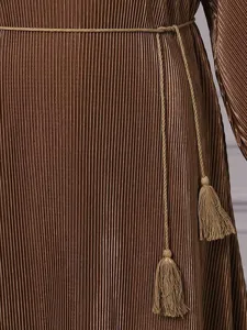 Detail shot showing the fine pleats and tassel belt of a solid color kaftan dress.