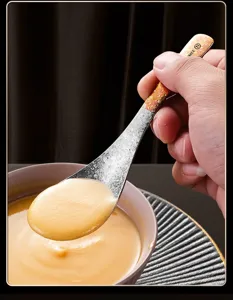 Nahaufnahme eines Suppenlöffels aus reinem Titan mit strukturiertem Griff beim Schöpfen.