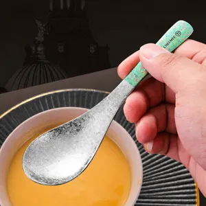 Cucchiaio da zuppa in titanio puro con manico lungo, impugnatura verde e texture martellata.