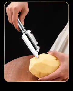 Stainless steel potato peeler detail showing sharp blade and ergonomic handle cutting.