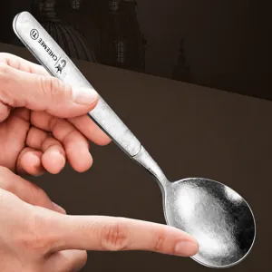 Cuillère à soupe haut de gamme en pur titane avec texture martelée et bord lisse et rond.