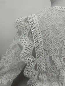 Close-up of white lace crop top sleeve, intricate hollow cutout floral details, fashion style.