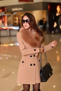 Vue de détail de l'élégant manteau en laine camel pour femme avec col en fourrure et croisé.