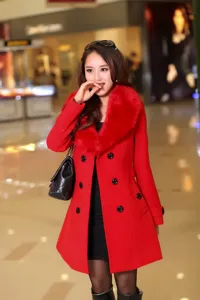 Vue détaillée d'un manteau de laine rouge pour femme avec col en fourrure et double boutonnage.