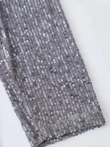 Détail de manche de blazer à sequins gris, tissu en maille scintillant, vêtement élégant.