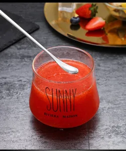 Long handled stainless steel mixing spoon and clear glass cup for daily kitchen use.