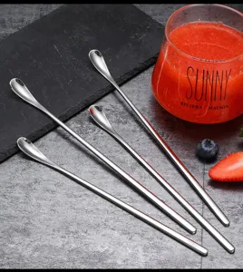Detailed close-up view of long stainless steel mixing spoons on textured slate and table.