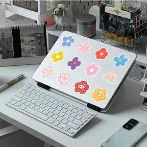 Close-up detail of colorful cartoon flower aesthetic stickers on a laptop surface.