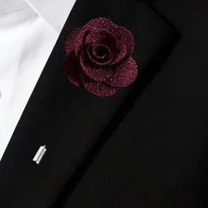 Detailed close-up view of a dark red glitter fabric rose brooch pinned on black suit.