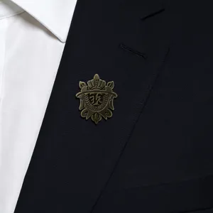 Close-up detail of vintage bronze crown shield brooch pinned on elegant men suit lapel.