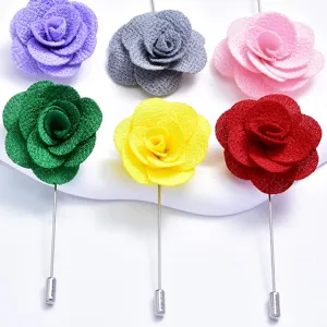 Detailed view of colorful fabric rose lapel pins with metal stems for wedding decoration.