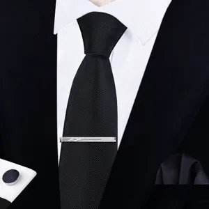 Detalle de primer plano de lujosa corbata negra texturizada, alfiler de corbata y gemelos elegantes.