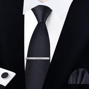 Vista detallada de corbata de hombre negra a rayas, pinza, pañuelo de bolsillo y gemelo formal.