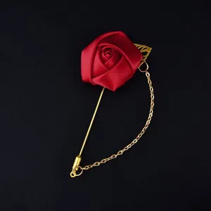 Red satin rose brooch with gold tone long pin and hanging chain detail closeup display
