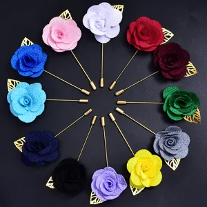 Gros plan détaillé de broches en tissu coloré en forme de rose avec des feuilles dorées.