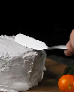 Détail de couteau à beurre en acier inoxydable montrant la lame lisse étalant de la crème.