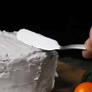 Couteau à beurre en acier inoxydable et spatule à confiture étalant de la crème blanche.