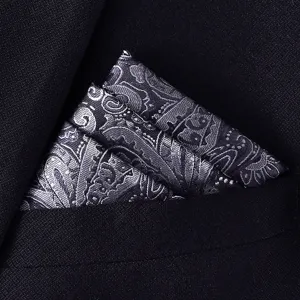 Detailopname van een zilveren paisley pochette, netjes gevouwen in de borstzak van een donker pak.