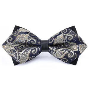 Close up of exquisite pointed bow tie with intricate gold and silver paisley pattern.