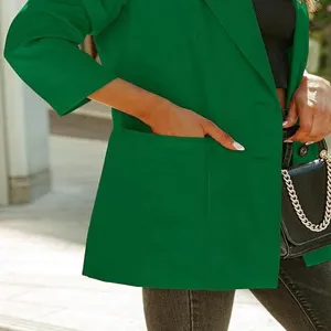 Détail de veste blazer verte avec col à revers, manches longues et poches avant.