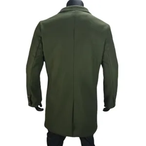 Detail shot showing the back design of a dark green men's wool coat with lapel and split hem.