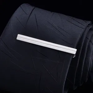 Close-up detail of silver-colored metal tie clip paired with black geometric pattern tie.