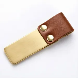 Close-up detail of vintage brass clip with brown leather loop and metal rivets for journal.