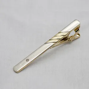Close-up detail of golden metal business tie clip featuring delicate crystal accent.