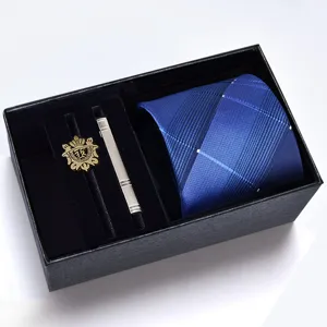 Details of the blue striped tie, golden brooch, and silver tie clip set in a black box.