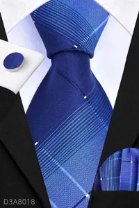 Detail view of blue business necktie fabric texture, matching pocket square and cufflink set.