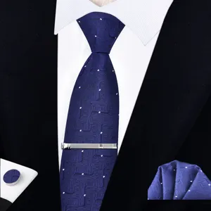Detalle de corbata geométrica azul oscuro con textura, pañuelo y pinza plateada.