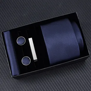 Detailed shot of men's dark blue business tie set including matching pocket square and cufflinks.