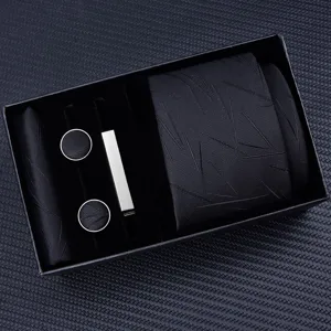 Black men's tie gift set detail showcasing texture, cufflinks, tie clip, and pocket square.