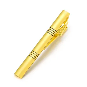 Close-up detail of a sleek golden brass tie clip with elegant striped accents for men.