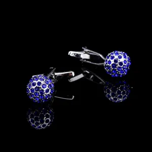 Detailed shot of French cufflinks featuring blue rhinestone spherical studs and silver metal.
