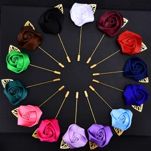 Detailed view of colorful fabric rose lapel pins with gold stems for wedding event decor.