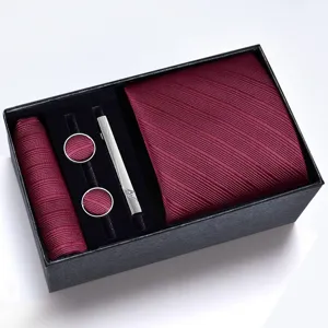 Gros plan sur la cravate bordeaux avec pochette assortie, boutons de manchette et pince à cravate.