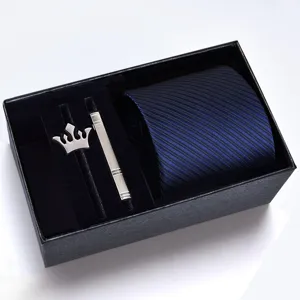 Close-up view of men's striped necktie, metallic tie clip and crown brooch inside gift box.
