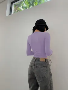 Detail view of a stylish women's long sleeve crop top in purple, paired with casual jeans.