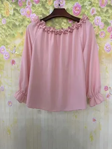 Vista dettagliata della blusa rosa a maniche lunghe con spalle scoperte ed eleganti volant.