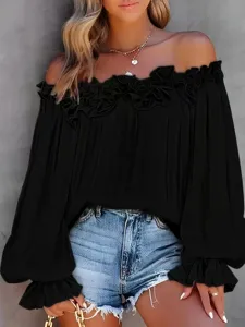 Primo piano dettagliato dell'elegante camicetta nera con maniche lunghe e spalle scoperte.