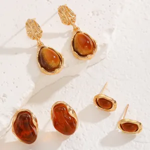 Gold-toned metal drop earrings and stud set featuring elegant amber-colored resin stones.
