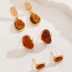 Detailed shot of gold-plated vintage resin amber earrings set, elegant jewelry pieces.