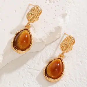 Detailed view of elegant teardrop gold earrings with shimmering brown stones for chic outfits.
