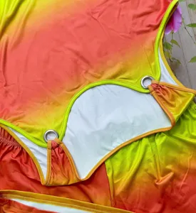 Dettaglio del set top smanicato e pantaloncini sfumati, con anelli in metallo e colori vivaci.