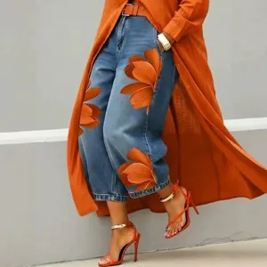 Nahaufnahme Detail von weiten Jeanshosen mit auffälligem orangem Blumen-Blüten-Print.